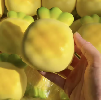 Squishy piña amarilla con hojas verdes sostenido en una mano