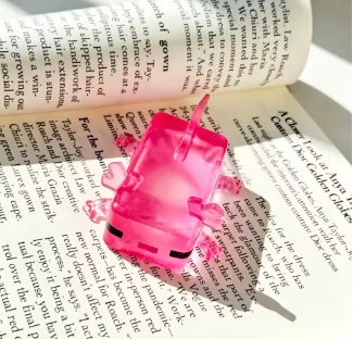 Squishy ajolote rosado transparente sobre paginas de un libro